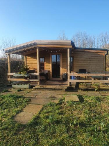 a small wooden house with a porch and a yard at Beautiful Wooden tiny house, Glamping cabin with hot tub 2 in Tuxford
