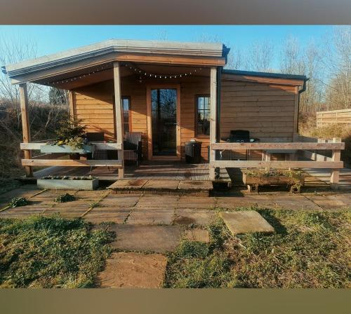 eine kleine Holzhütte mit einer Veranda und einem Tisch in der Unterkunft Beautiful Wooden tiny house, Glamping cabin with hot tub 2 in Tuxford
