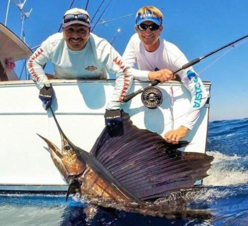 two people on a boat with a fish in the water at Hotel and Dive Center Roatan Yacht Club in Roatán