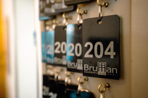 a sign hanging on a wall with gold hooks at Hotel Bruman Salerno in Salerno