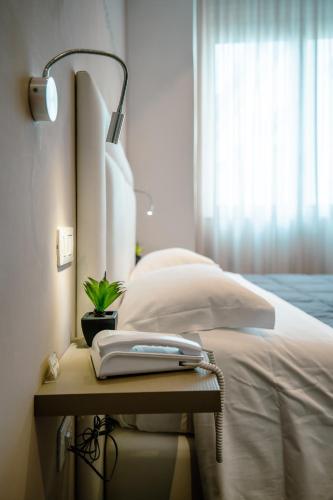 a bed with a phone on a table next to a window at Hotel Bruman Salerno in Salerno