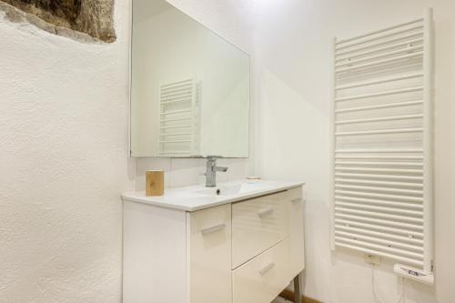 une salle de bain blanche avec un lavabo et un miroir dans l'établissement La Forge des Templiers, à Lorgues