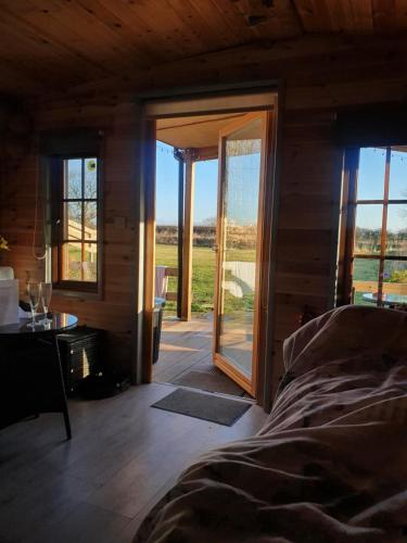a bedroom with a bed and a sliding glass door at Beautiful Wooden tiny house, Glamping cabin with hot tub 2 in Tuxford