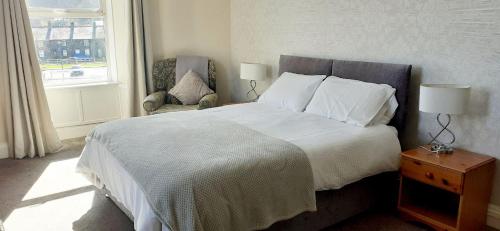 a bedroom with a bed and a chair and a window at Queens Rooms in Porthmadog