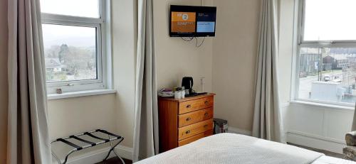 a bedroom with a bed and a tv on the wall at Queens Rooms in Porthmadog