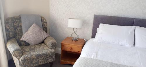 a bedroom with a bed and a chair and a lamp at Queens Rooms in Porthmadog