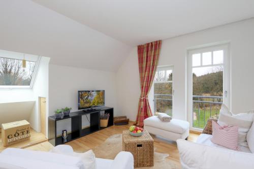 a living room with white furniture and a large window at Harz-Urlaubs-Alm Hotel & Ferienhäuser in Clausthal-Zellerfeld