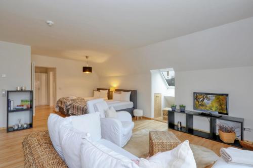 a living room with white furniture and a bed at Harz-Urlaubs-Alm Hotel & Ferienhäuser in Clausthal-Zellerfeld
