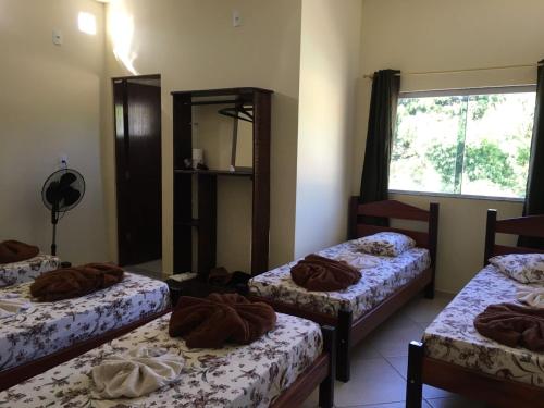 a room with three beds with brown blankets on them at Pousada Rota da Luz in Aparecida