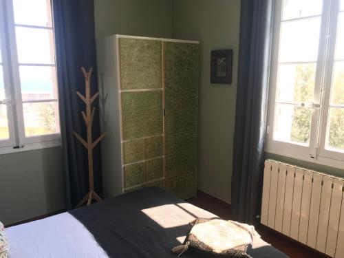 a bedroom with a bed and two windows at La chambre de Toutou in Bastia