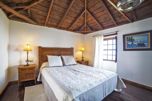 Un dormitorio con una cama y dos lámparas y una ventana. en Casa Tierras Viejas, en Tijarafe
