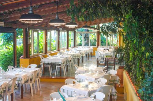 ein Restaurant mit weißen Tischen, Stühlen und Pflanzen in der Unterkunft Villaggio La Perla in Marina di Camerota