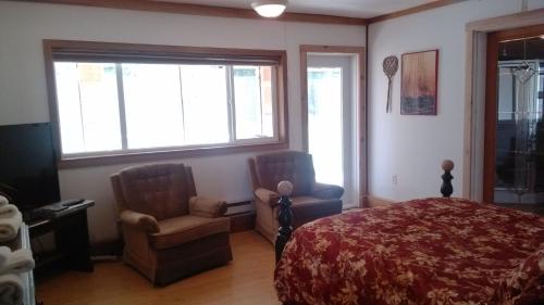 a bedroom with a bed and two chairs at Harrison Hammond House Farmstay in Harrison Mills