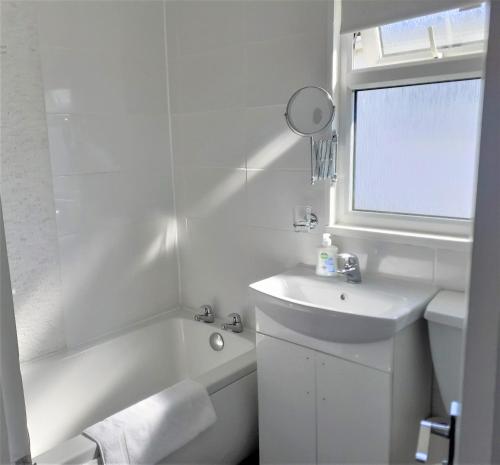 a white bathroom with a sink and a bath tub and a sink at Fabulous 2 bedroom dog friendly chalet 5 min walk to beach, nr Gt Yarmouth & Norfolk Broads in Scratby