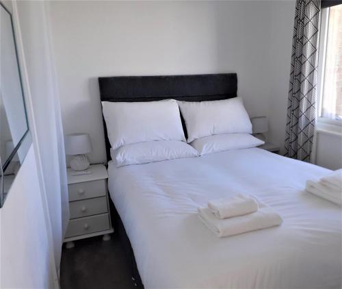 a bedroom with a white bed with two towels on it at Fabulous 2 bedroom dog friendly chalet 5 min walk to beach, nr Gt Yarmouth & Norfolk Broads in Scratby