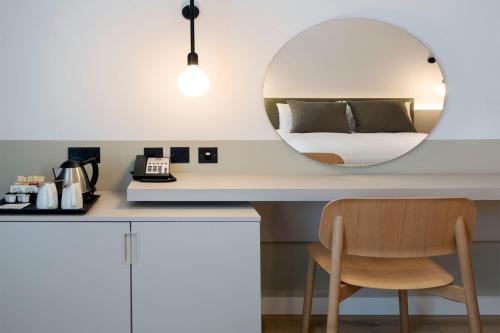 a bedroom with a mirror and a table with a chair at Leonardo Hotel Manchester Piccadilly in Manchester