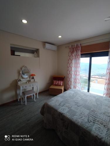 a bedroom with a bed and a table and a window at Casa Da Fonte Da Torre in Peso da Régua