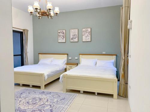 a bedroom with two beds and a chandelier at 歐森小鎮&歐文小鎮 in Jian