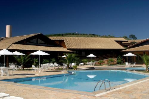 una piscina frente a un complejo con sillas y sombrillas en Canto da Floresta Ecoresort, en Amparo