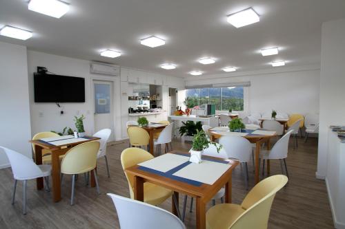 a dining room with tables and chairs and a tv at Hotel Don Zepe in Florianópolis