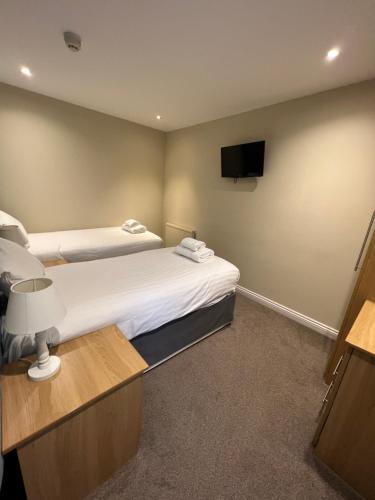 a hotel room with two beds and a flat screen tv at Stirk House Hotel in Clitheroe