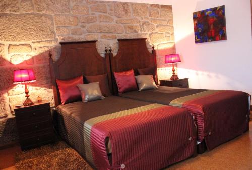 two beds in a room with two lamps on tables at Casa do Adro de Parada in Parada de Pinhão