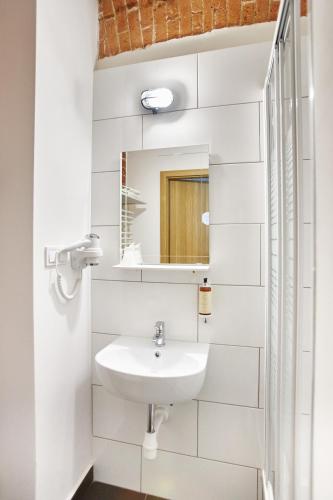 a white bathroom with a sink and a mirror at Koszary Arche Hotel in Góra Kalwaria