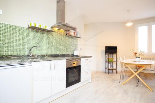 a kitchen with white cabinets and a table and a sink at Luanco 11 Apartamento ,centro de Gijón in Gijón