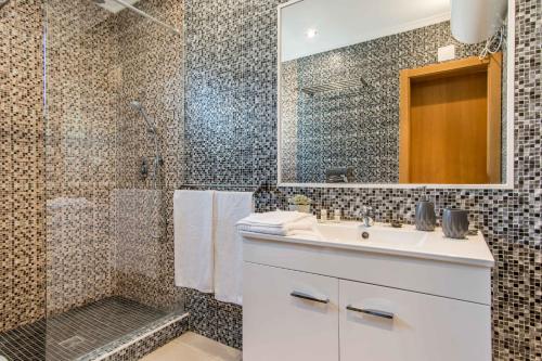 een badkamer met een witte wastafel en een douche bij Appartement Chaleureux et Lumineux Proche Mer in Albufeira