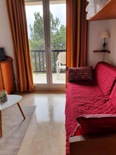 Il comprend un salon doté d'un lit rouge et d'un balcon. dans l'établissement Charmant studio face aux Pyrénées, à Font-Romeu-Odeillo-Via