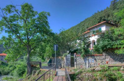 a building with a fence in front of a mountain at La casa sul fiume in Albisola Superiore