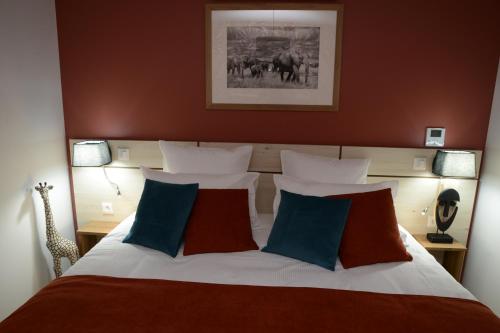 a bedroom with a large bed with blue and red pillows at L'Hostellerie d'Acquigny in Acquigny