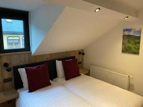 Schlafzimmer mit einem Bett mit weißer Bettwäsche und roten Kissen in der Unterkunft Rouleur Houffalize in Houffalize