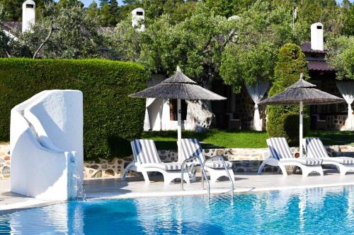 a group of chairs and umbrellas next to a swimming pool at Acrotel Athena Residence in Elia
