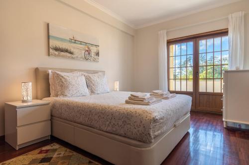 a white bedroom with a bed and a window at Casa Miha in Sintra