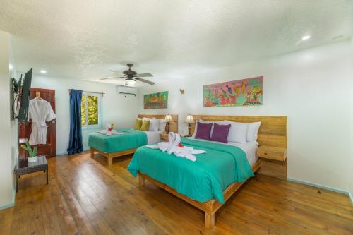 a bedroom with two beds and a ceiling fan at Hotel and Dive Center Roatan Yacht Club in Roatán