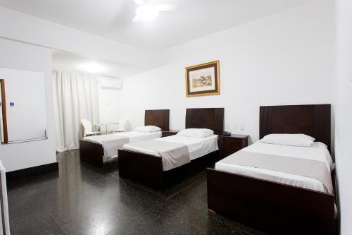 una habitación de hotel con 2 camas y una silla en Savassi Hotel en Belo Horizonte