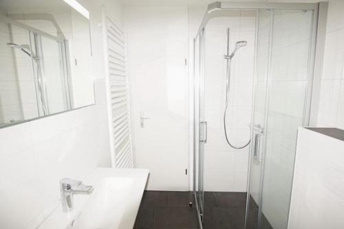 een witte badkamer met een douche en een wastafel bij Urlauberdorf Urlauberdorf 49d in Boltenhagen