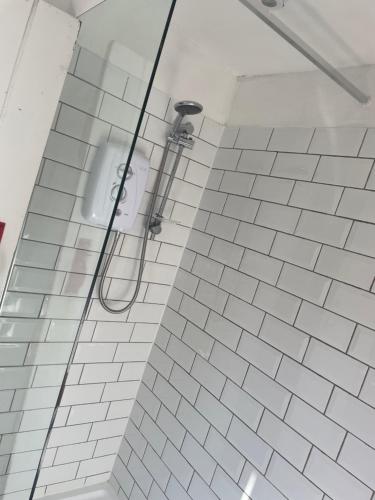 a shower in a bathroom with white tiles at Penhallow House in Newlyn East