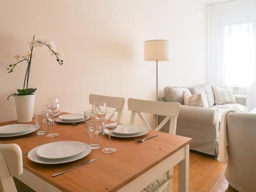 Una mesa de comedor con platos y copas de vino encima. en FilinHome Papa Suite 4, en Novi Sad