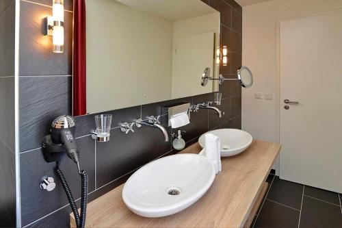 a bathroom with two sinks and a large mirror at Resort Deichgraf Resort Deichgraf 31-02 in Wremen