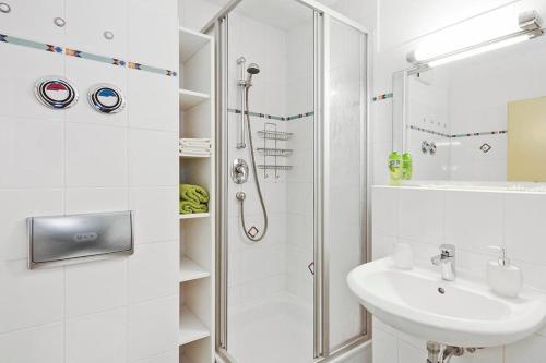 ein weißes Bad mit einer Dusche und einem Waschbecken in der Unterkunft Strand-Park Strand-Park 213 in Heringsdorf