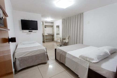 a hotel room with two beds and a flat screen tv at Savassi Hotel in Belo Horizonte