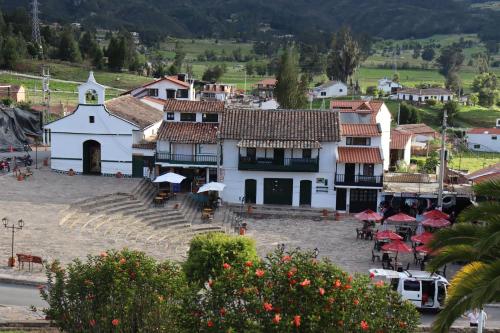 a village with a white building and a church at Hotel Lancers - Pantano de Vargas in Paipa