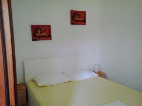 um quarto com uma cama branca e duas fotografias na parede em Apartment in Novi Vinodolski with Sea View, Terrace, Wifi, Washing Machine (3667-2) em Novi Vinodolski