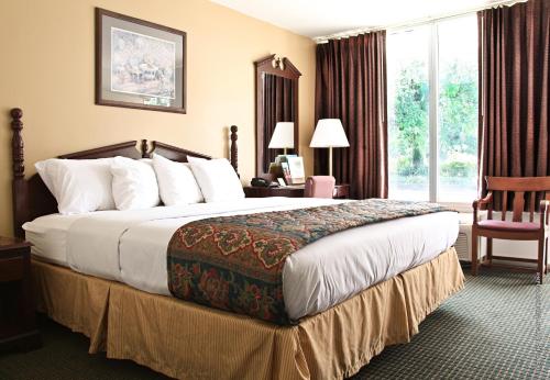 a hotel room with a large bed and a window at Carmel Inn and Suites Thibodaux in Thibodaux