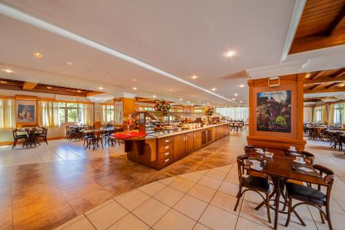 un ristorante con bar, tavoli e sedie di Hotel Laghetto Siena Gramado a Gramado