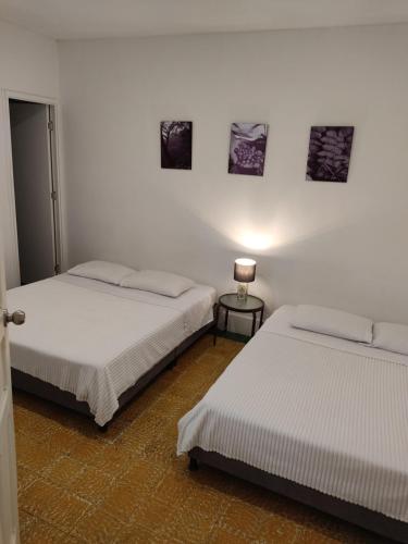 a room with two beds and a lamp on a table at Hotel San Telmo in Buga