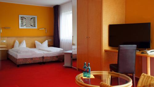 um quarto de hotel com uma cama e uma televisão de ecrã plano em Hotel am Buschkrugpark em Berlim
