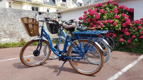 two bikes parked in a parking lot with flowers at Les Chants d'Ailes - Hôtel Face Mer in La Turballe